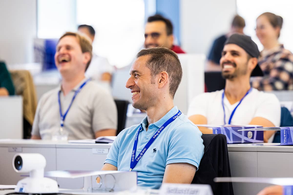 Männliche Führungskräfte lachen während einer EMBA-Vorlesung 