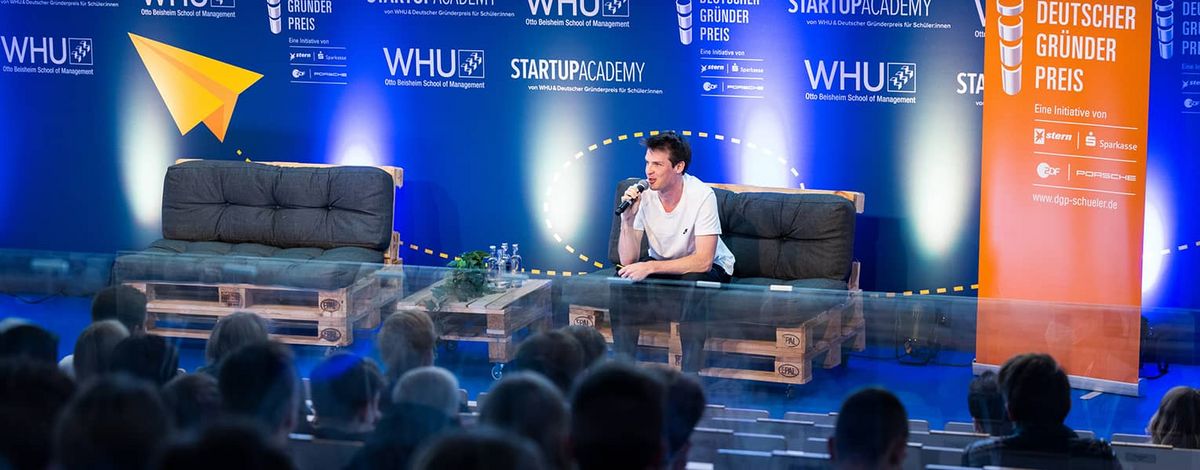 Ein sitzender Redner spricht auf der Bühne der WHU Start-Up Academy 2021