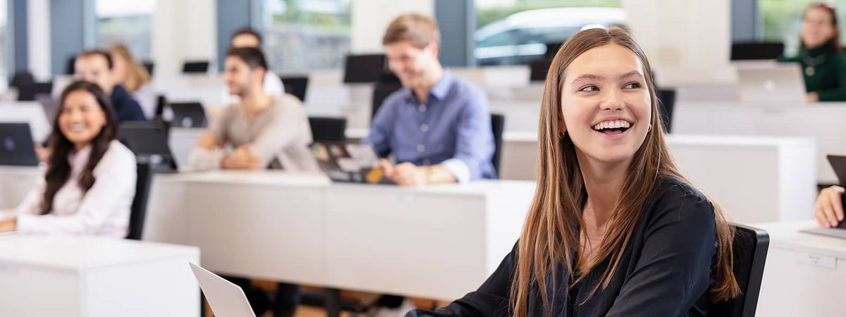 [Translate to English:] Eine lächelnde weibliche Studierende bei der Vorlesung