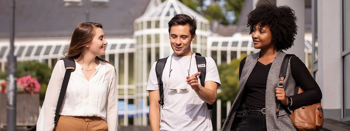 Three students talking as they walk through Campus Vallendar